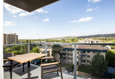 a balcony with a wooden table and chairs at Pomeroy Hotel Fort McMurray in Fort McMurray