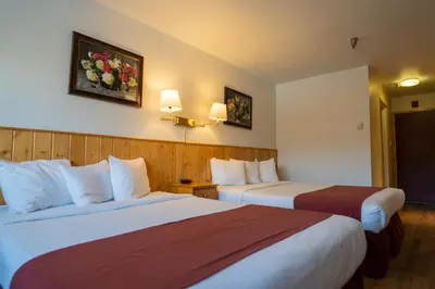 a hotel room with two beds and two pictures on the wall at Canadas Best Value Inn- Riverview Hotel in Whitehorse