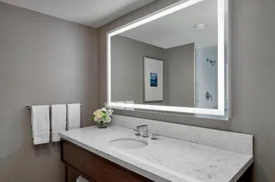 a bathroom with a sink and a large mirror at Sheraton Vancouver Guildford Hotel in Surrey