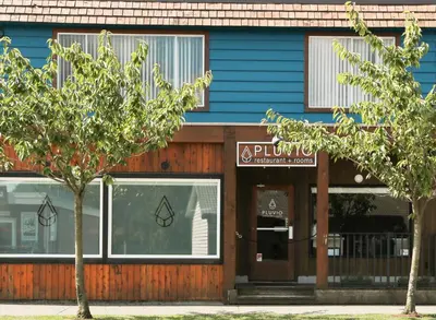 a blue building with trees in front of it at Pluvio restaurant and rooms in Ucluelet