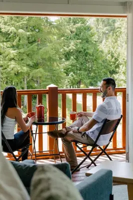 a man and woman sitting at a table on a porch at Pluvio restaurant and rooms in Ucluelet