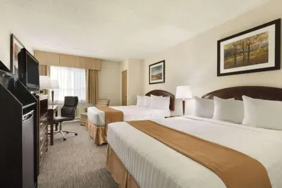 a hotel room with two beds and a flat screen tv at Travelodge by Wyndham Edmonton South in Edmonton