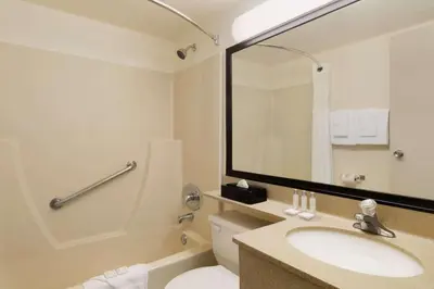 a bathroom with a sink and a toilet and a mirror at Travelodge by Wyndham Edmonton South in Edmonton
