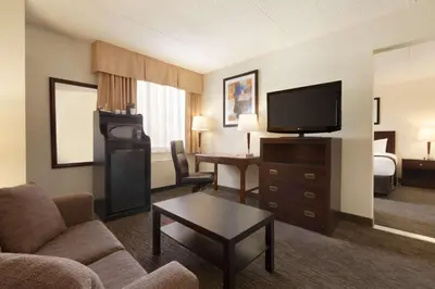 a living room with a couch and a television in a hotel room at Travelodge by Wyndham Edmonton South in Edmonton