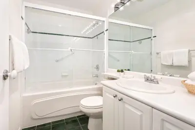 a white bathroom with a tub and a toilet and a sink at Bear Lodge (Town Plaza) in Whistler