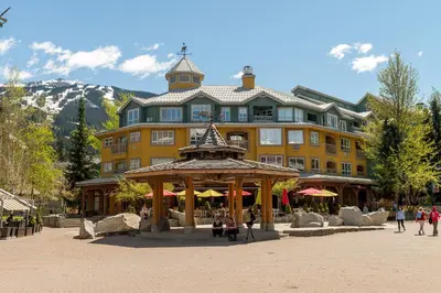 a large yellow building with a gazebo in front of it at Bear Lodge (Town Plaza) in Whistler