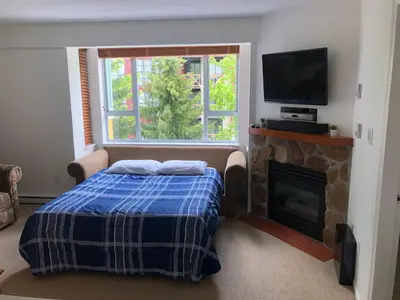 a bedroom with a bed and a fireplace and a television at Bear Lodge (Town Plaza) in Whistler