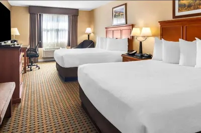 a hotel room with two beds and a desk at Best Western Plus Osoyoos Hotel & Suites in Osoyoos