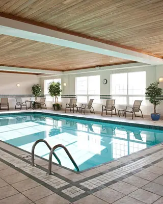a pool in a hotel with chairs and tables at Country Inn & Suites by Radisson, Calgary-Northeast in Calgary