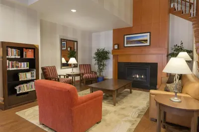 a living room with a fireplace and a chair at Country Inn & Suites by Radisson, Calgary-Northeast in Calgary