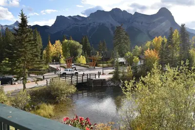 a bridge over a river with mountains in the background at The Drake Inn in Canmore
