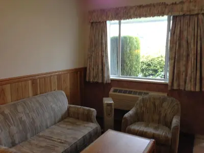 a living room with a couch and a chair and a window at Rainbow Motor Inn in Chilliwack