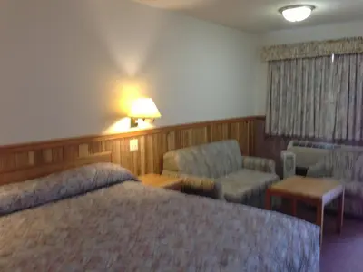 a hotel room with a bed and a chair at Rainbow Motor Inn in Chilliwack