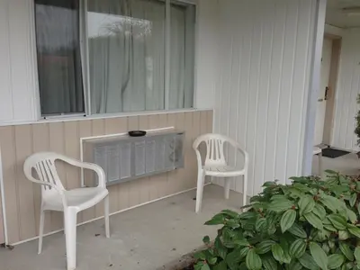 two white chairs and a television on a porch at Rainbow Motor Inn in Chilliwack