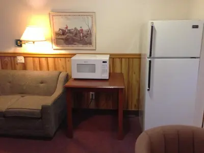 a kitchen with a refrigerator and a table with a microwave at Rainbow Motor Inn in Chilliwack