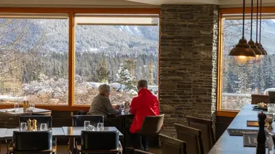 two people sitting at a table in a restaurant with a view at The Juniper Hotel & Bistro in Banff