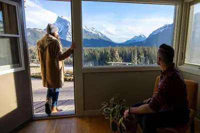 two people looking out the window of a house at The Juniper Hotel & Bistro in Banff