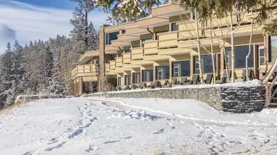 a building in the snow with a snow covered driveway at The Juniper Hotel & Bistro in Banff