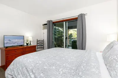a white bedroom with a bed and a television at Glaciers Reach by Allseason Vacation Rentals in Whistler