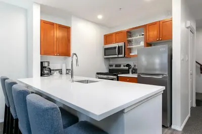 a kitchen with a white counter top and wooden cabinets at Glaciers Reach by Allseason Vacation Rentals in Whistler
