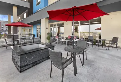 a patio with tables and chairs and a red umbrella at TownePlace Suites by Marriott Edmonton Sherwood Park in Sherwood Park