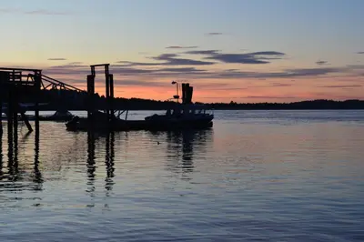 a dock with a boat in the water at sunset at Island Village Properties at Fred Tibbs in Tofino