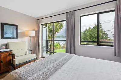 a bedroom with a bed and a chair and a window at Tofino Motel Harbourview in Tofino