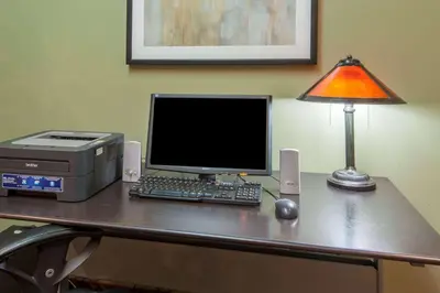 a desk with a computer and a lamp on it at Super 8 by Wyndham Cochrane in Cochrane