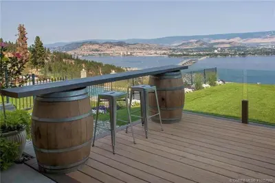 a deck with two barrels and a table on top at Lake and Bridge View Vacation Home in West Kelowna