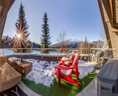 a patio with two red chairs and snow on the grass at THE LOOKOUT PENTHOUSE // a luxe suite in Whistler in Whistler