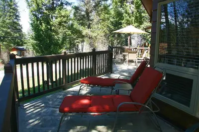 a porch with two red chairs and an umbrella at Falcon Cabin in Fairmont Hot Springs