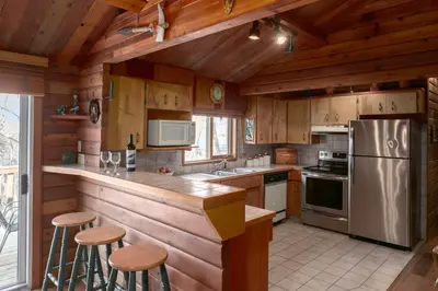a kitchen with wooden cabinets and a stainless steel refrigerator at Creekside Cabin in Fairmont Hot Springs