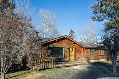a log cabin with a porch and a yellow door at Creekside Cabin in Fairmont Hot Springs