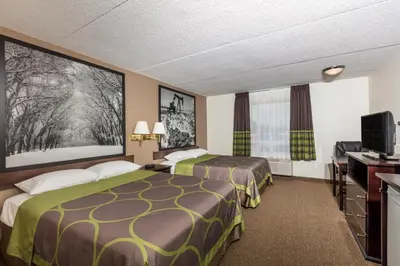 a hotel room with two beds and a flat screen tv at Super 8 by Wyndham Edson in Edson