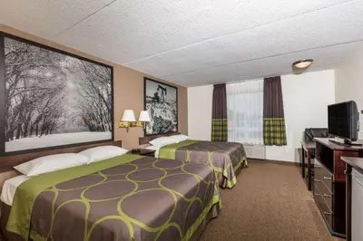 a hotel room with two beds and a flat screen tv at Super 8 by Wyndham Edson in Edson