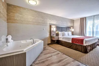 a hotel room with a bed and a bath tub at Comfort Inn & Suites South in Calgary