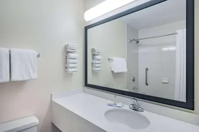 a white bathroom with a sink and a large mirror at Travelodge by Wyndham Fort St John in Fort Saint John