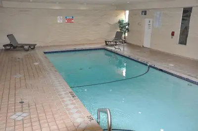 a large swimming pool with two chairs in a building at Ramada by Wyndham Abbotsford in Abbotsford