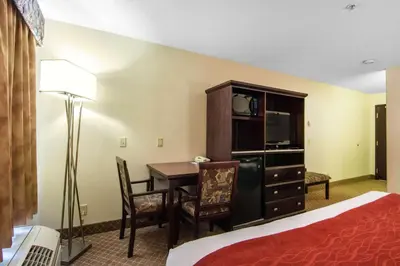 a hotel room with a desk and a bed and a room at Comfort Inn & Suites Airport South in Calgary