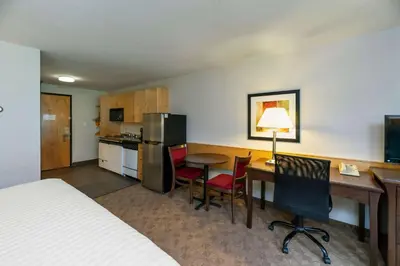 a hotel room with a bed and a desk and a kitchen at Prestige Riverside Lodge Quesnel in Quesnel