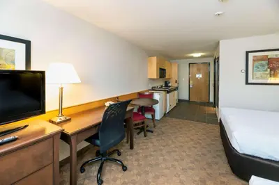 a hotel room with a bed and a desk with a computer at Prestige Riverside Lodge Quesnel in Quesnel