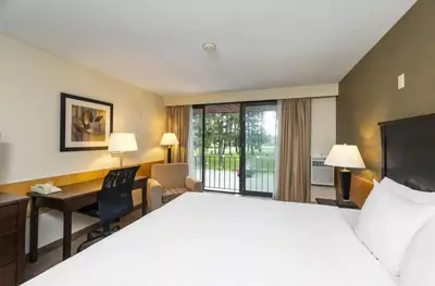 a hotel room with a large bed and a desk at Prestige Riverside Lodge Quesnel in Quesnel