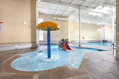 a pool with a slide in the water at Sundance Suite - Beautiful Condo With Open Pool And Hot Tub in Canmore