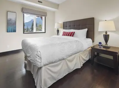 a bedroom with a large bed and a table at Sundance Suite - Beautiful Condo With Open Pool And Hot Tub in Canmore