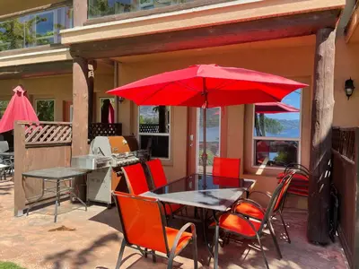 a table and chairs with a red umbrella on a patio at Lakefront Townhouse Family Complex, Popular Wine Country and the Best Golfing in Osoyoos