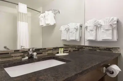 a bathroom with a sink and a mirror and towels at Travelodge by Wyndham Calgary South in Calgary
