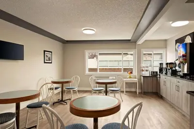 a room with tables and chairs and a kitchen at Travelodge by Wyndham Calgary South in Calgary