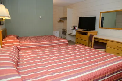 a hotel room with two beds and a desk and a television at Plains Motel in Brooks