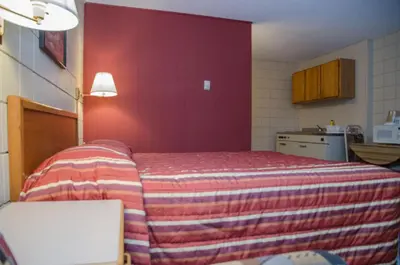 a bedroom with a bed with a red wall at Plains Motel in Brooks