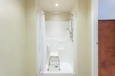 a white shower with a chair in a bathroom at Super 8 by Wyndham Abbotsford BC in Abbotsford